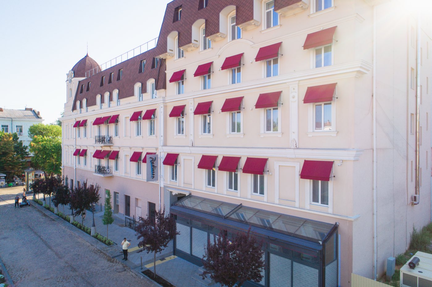 Klassiek hotel met rode uitvalschermen op maat in de zon