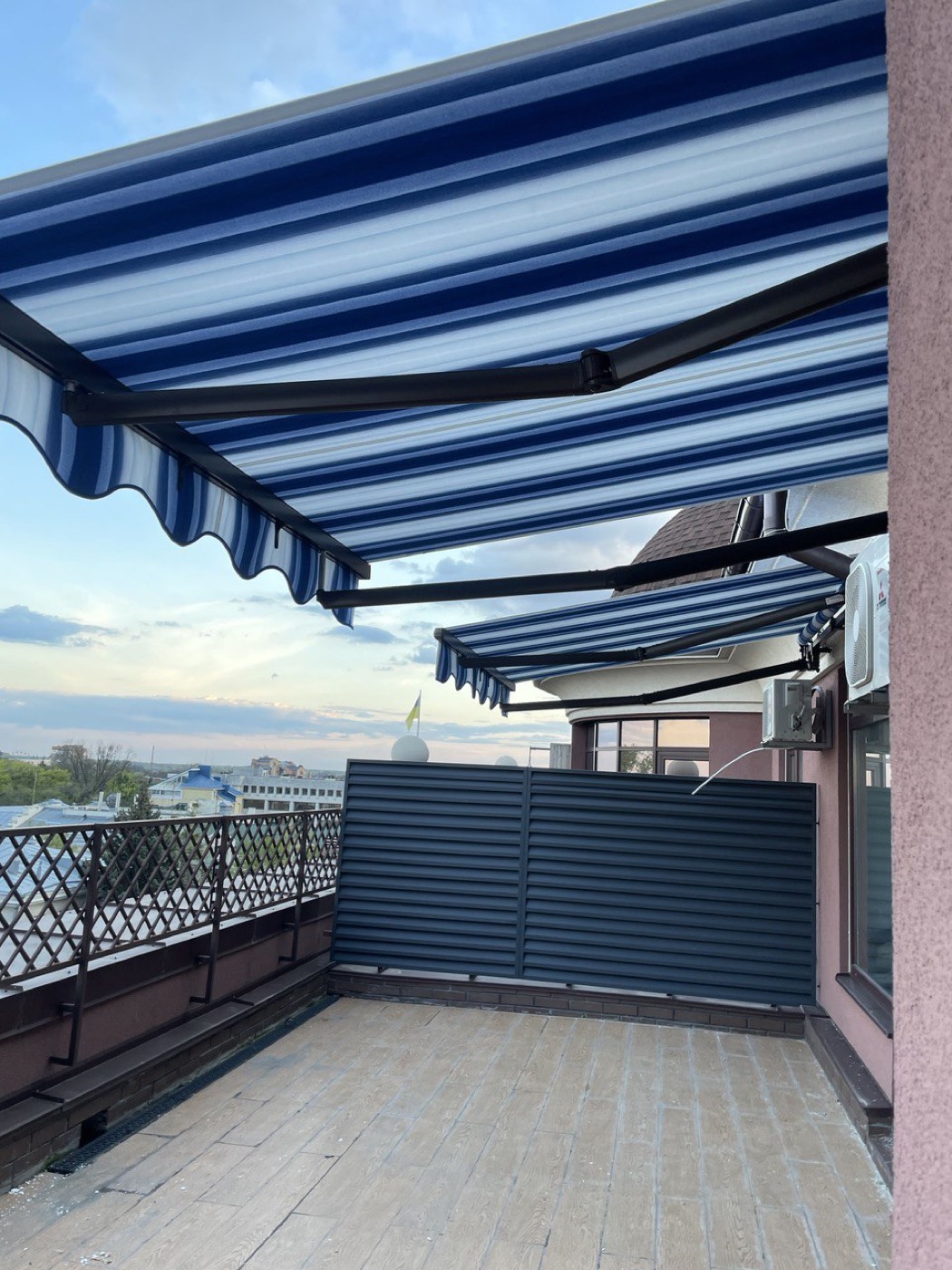 Blauw-wit gestreepte knikarmschermen op een dakterras