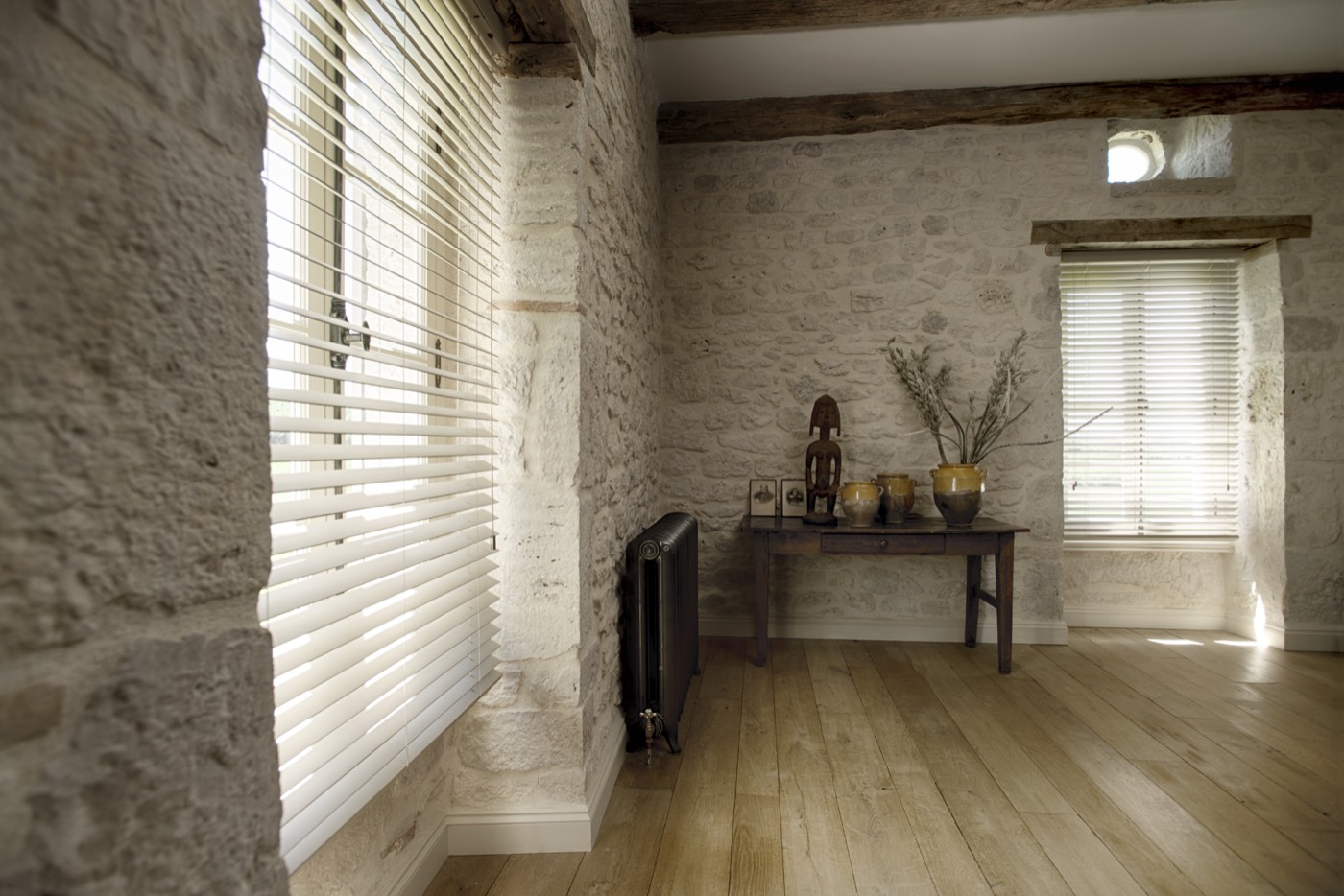 Houten jaloezieën in een landelijk interieur met natuurstenen muur